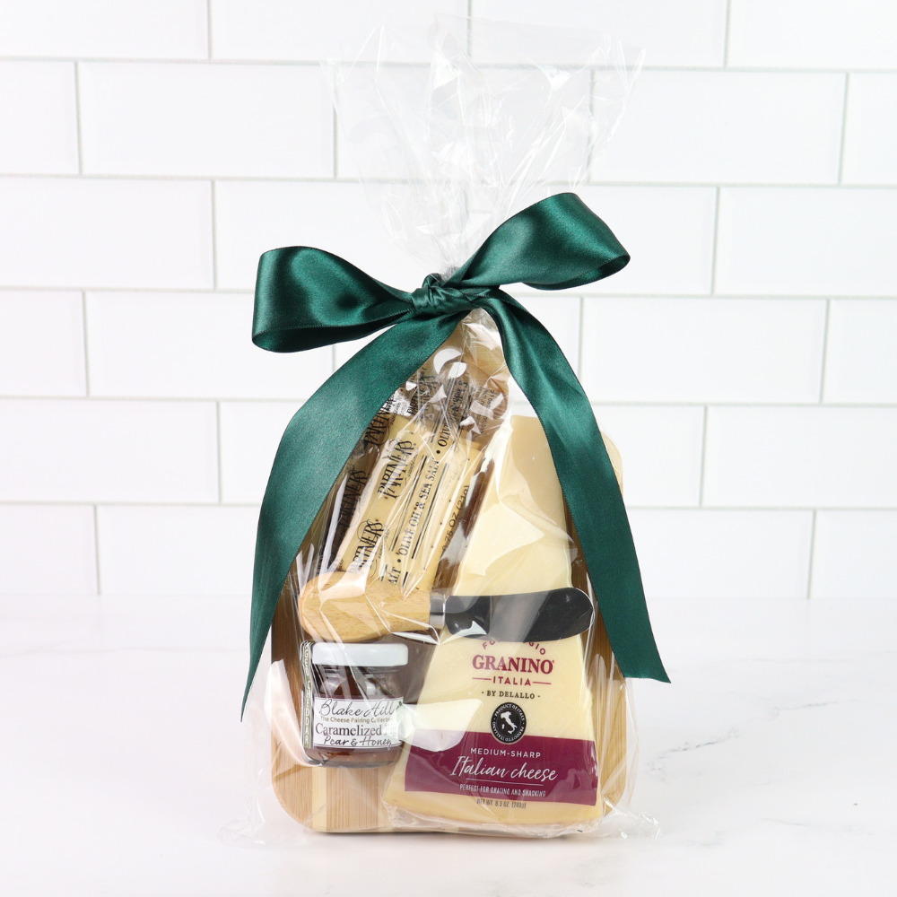 Packaged cheese with a green ribbon on a white tiled background