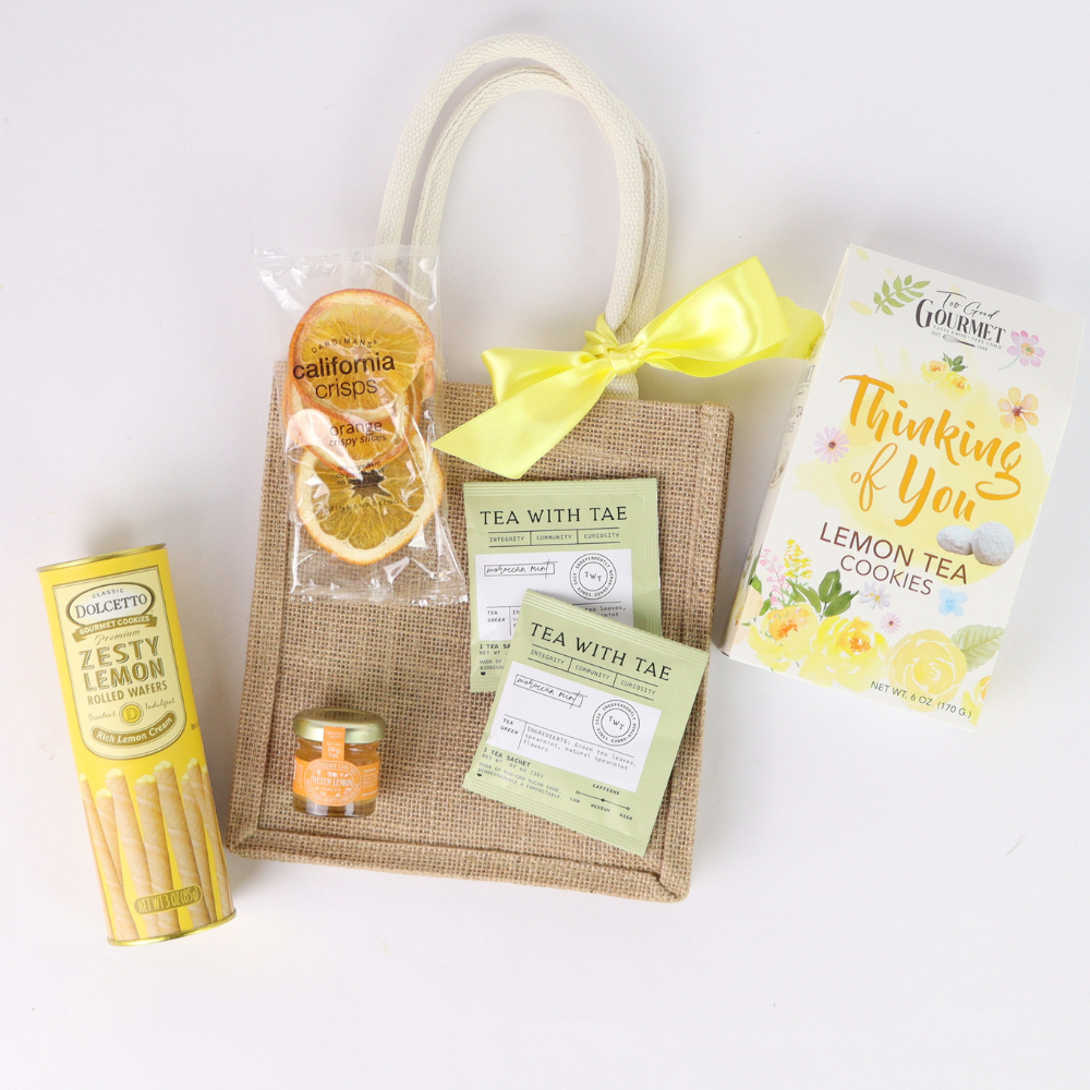 Gift set with lemon-themed products including cookies, tea, and cookies on a white background