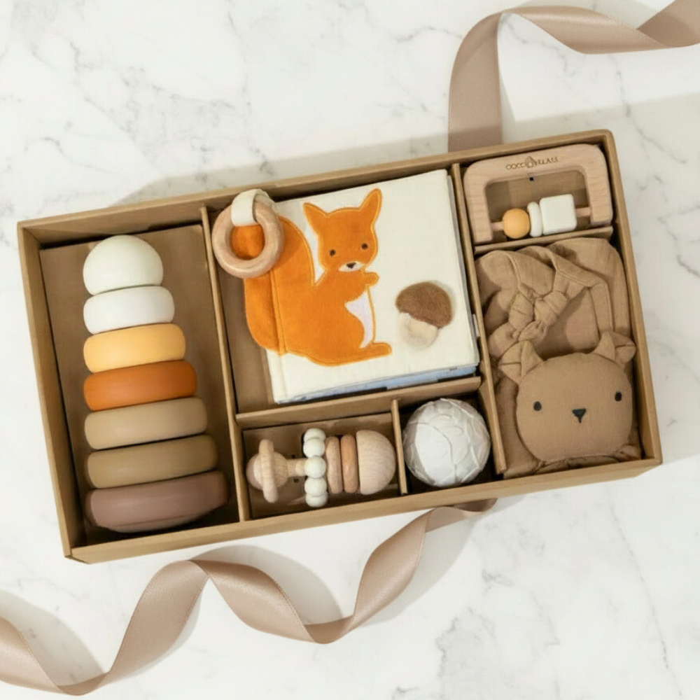 Collection of baby toys in a box on a white marble surface