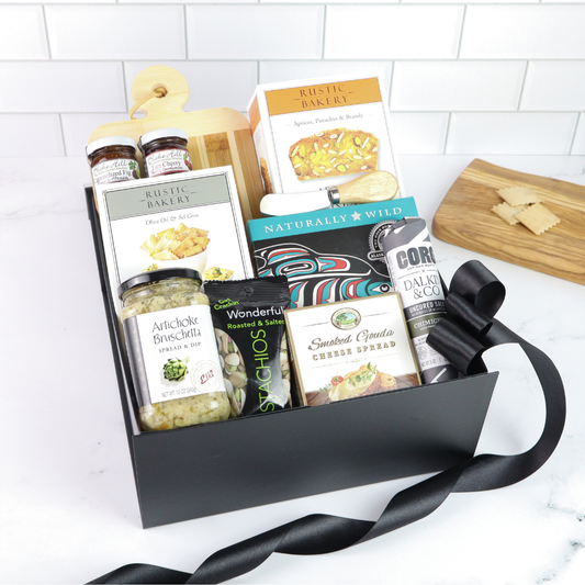 Gift basket with various food items on a white surface with a tiled wall background