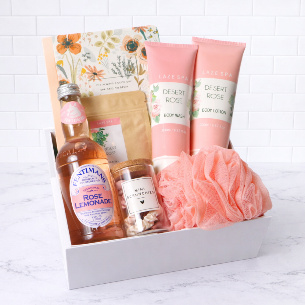 Gift set with body care products including bottles, jars, and bath pouf on a white background