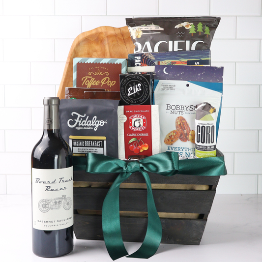 Gift basket with wine, cheese, and snacks on a white background